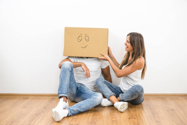 L'homme avec une boîte en carton sur une tête s'assoit près de la femme - Photo, image