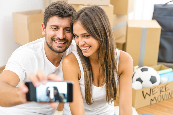 La joven pareja hace una foto en el fondo de las cajas de cartón - Foto, imagen
