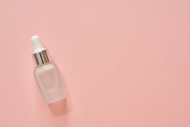 A glass bottle of aromatherapy essential oil on pastel pink background, with copy space. Top view. - Фото, изображение
