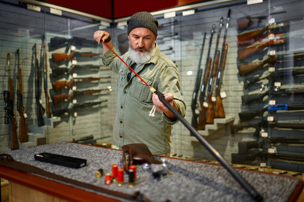 Barbuto maschio cacciatore scegliendo ramrod in negozio di armi - Foto, immagini