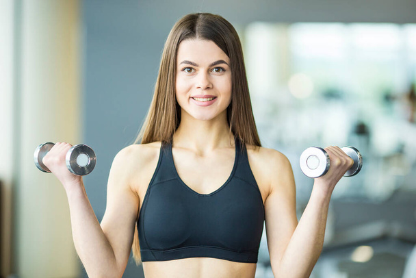 The sportswoman doing exercise with dumbbells in the gym - Photo, Image