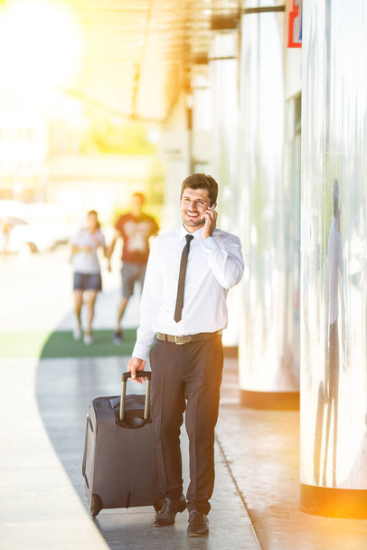 Ο επιχειρηματίας τηλέφωνο και να περπατήσει με μια βαλίτσα - Φωτογραφία, εικόνα