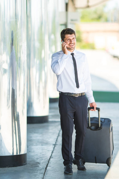 El hombre de negocios llama y camina con una maleta - Foto, imagen