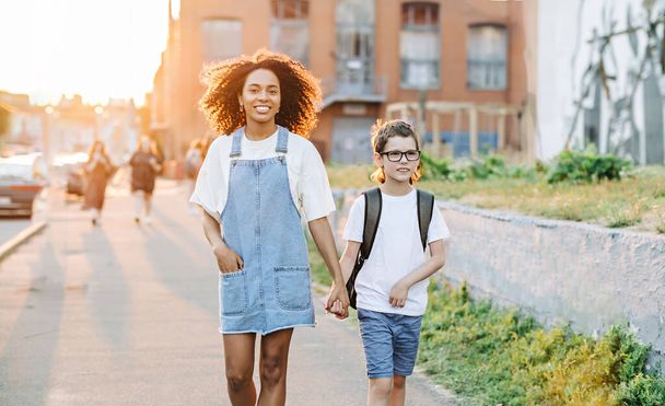 家庭教師と自閉症の少年は日の出に外の学校に戻って歩く。自閉症の子供と学校の概念に戻る - 写真・画像