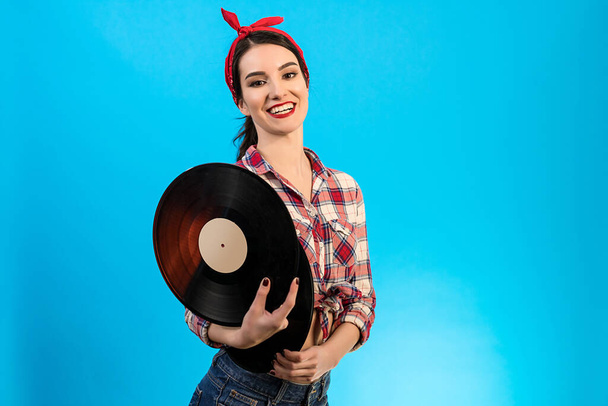 The attractive woman holding a vinyl record on the blue background - Фото, зображення