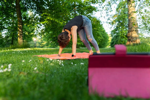 Jovem atraente praticando ioga após um vídeo mostrado em seu tablet no parque durante uma noite de verão no Hyde Park, Londres - Foto, Imagem