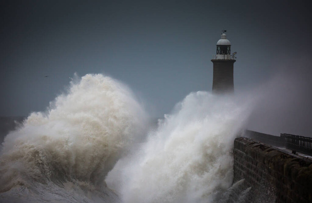 イギリス、タイネマスのタインの口を守る灯台と北の桟橋に打ち寄せる巨大な波 - 写真・画像