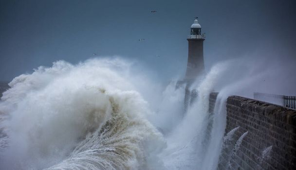 Велетенські хвилі б "ють маяк і північний пірс, охороняючи гирло річки Тайн у Тинемуті (Англія). - Фото, зображення