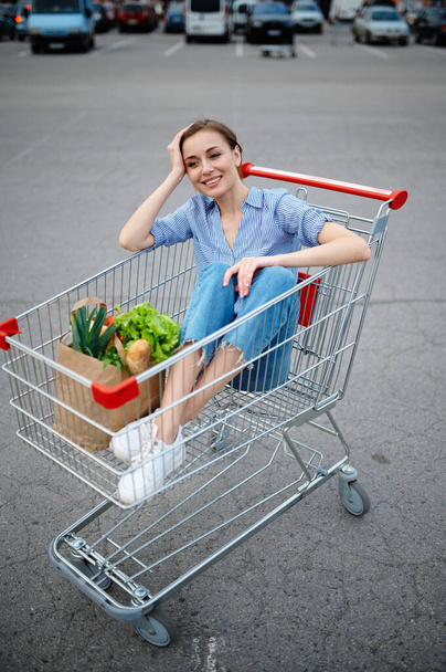 Mulher engraçada sentada no carrinho no estacionamento do supermercado - Foto, Imagem