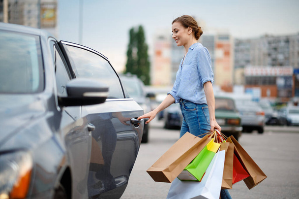 Woman puts her purchases in car on market parking - Φωτογραφία, εικόνα
