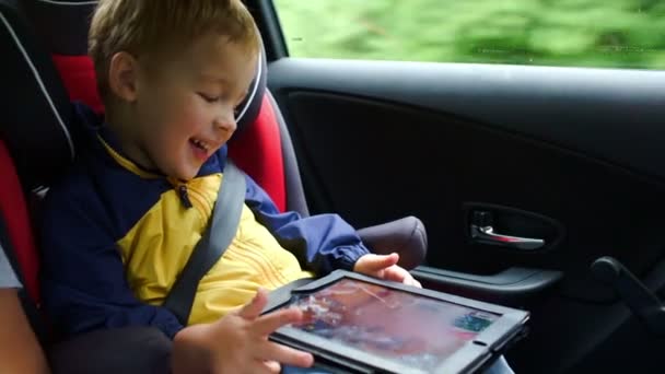 liten pojke spelar på tablet PC i bilen - 映像、動画