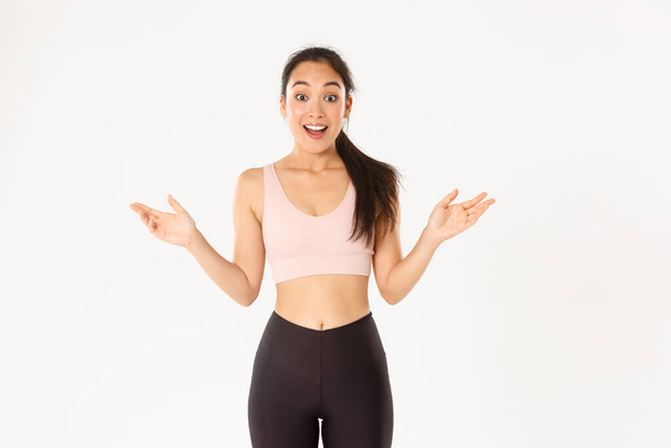 Sport, wellbeing and active lifestyle concept. Surprised and excited asian sportswoman hear about great discounts for workout equipment, gym membership, fitness girl looking amazed - Photo, Image