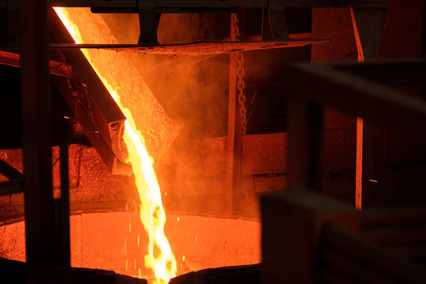 metal fundido del horno se vierte por el conducto en la cuba. pulverización de metal caliente primera etapa para la producción - Foto, imagen