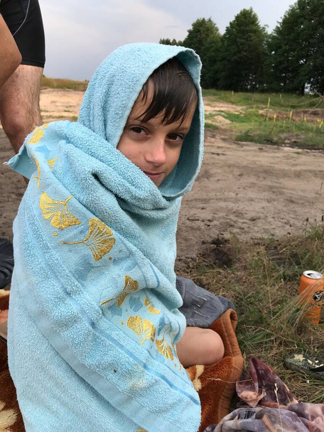 Niño mojado sentado en una toalla después de nadar en el río  - Foto, imagen
