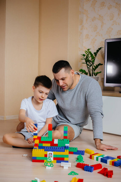 Um menino em conjunto com seu pai é interpretado por um construtor e constrói uma casa. Construção de uma casa de família. - Foto, Imagem