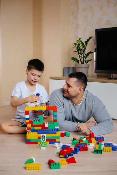 A little boy together with his father is played by a constructor and builds a house. Construction of a family home. - Foto, Imagen
