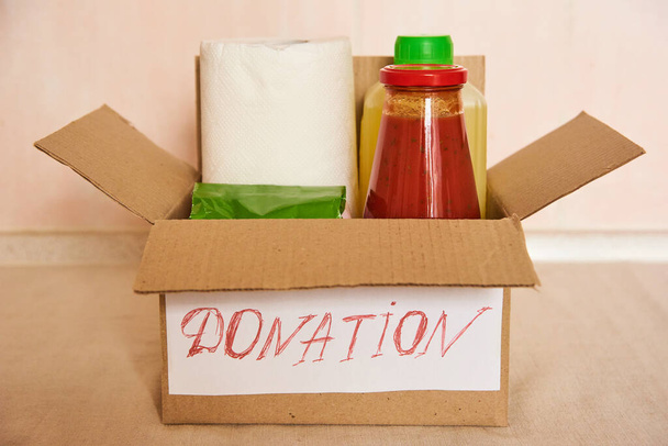 Volledige donatie doos op keukentafel. Voedselleveringsconcept. arme gezinnen en ouderen helpen - Foto, afbeelding