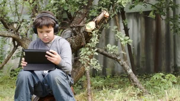 Adolescente em fones de ouvido usando touchpad ao ar livre
 - Filmagem, Vídeo