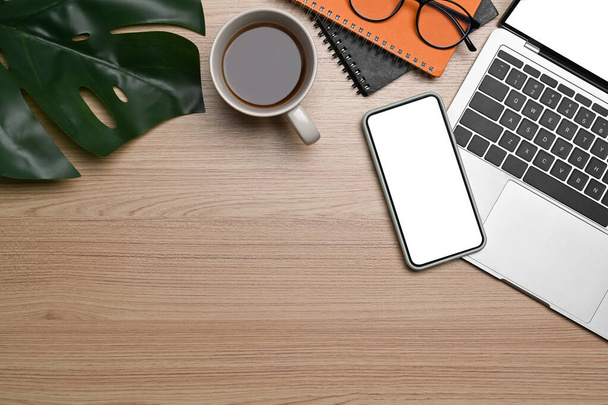 Vista dall'alto smart phone, laptop, notebook, bicchieri e tazza di caffè su sfondo di legno. - Foto, immagini