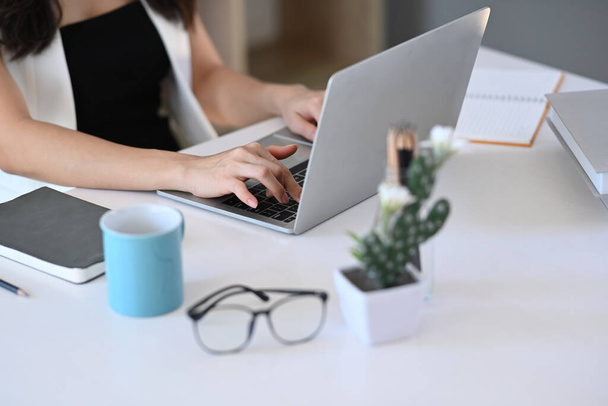 Обрезанный снимок молодой женщины, работающей с ноутбуком на белом офисном столе. - Фото, изображение