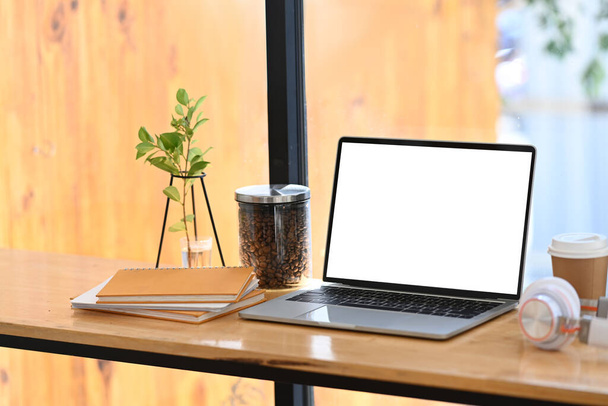 Mock up számítógép laptop üres képernyőn, fejhallgató, kávé csésze és notebook fából készült asztalon. - Fotó, kép
