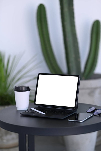 Компьютер, ноутбук и чашка кофе на черном столе в кофейне. - Фото, изображение
