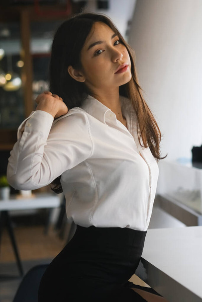 Portrait of businesswoman relaxing and stretching her arms in office. - Foto, imagen