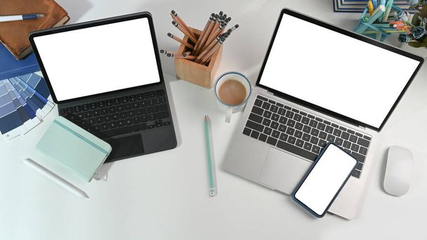 Espaço de trabalho de designer gráfico com tablet de computador, laptop, telefone inteligente e papelaria na mesa branca. - Foto, Imagem