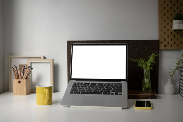 Mock up computer laptop, Coffe cup, kamerplant, smartphone en potlood houder op wit bureau. - Foto, afbeelding