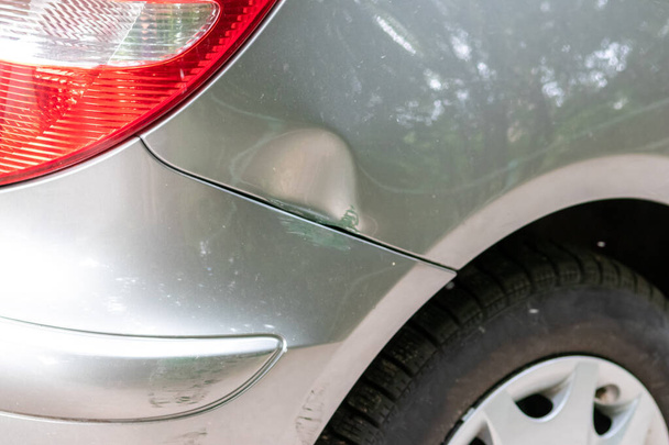 Dented car wing and fender with scratches and bumps after crash and car accident with hit-and-run driving and absconding shows need for car insurance and safety protection and mechanics garage service - Foto, Bild