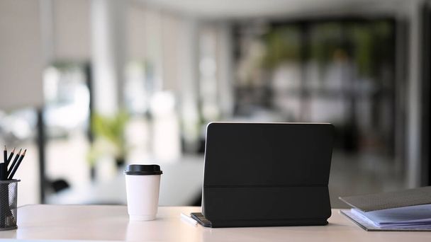 Számítógépes tabletta, kávéscsésze, dokumentum és ceruzatartó fehér irodai asztalon. - Fotó, kép