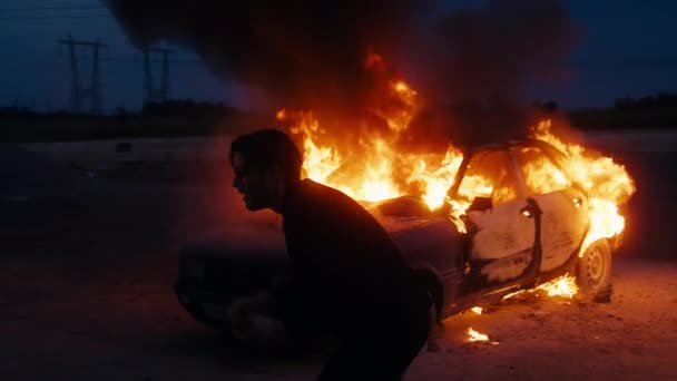 Az ember megragadja a fejét, nagyon feldúlt az égett autó miatt a tűzben.. - Felvétel, videó