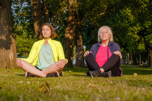 Großmutter und Enkelin meditieren gemeinsam im Park. - Foto, Bild