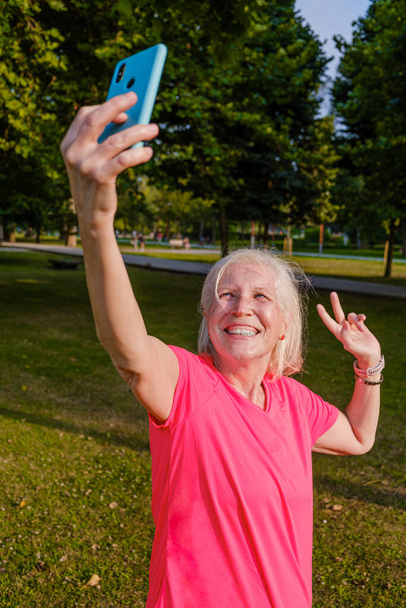 Sportiva anziana che si fotografa nel parco. - Foto, immagini