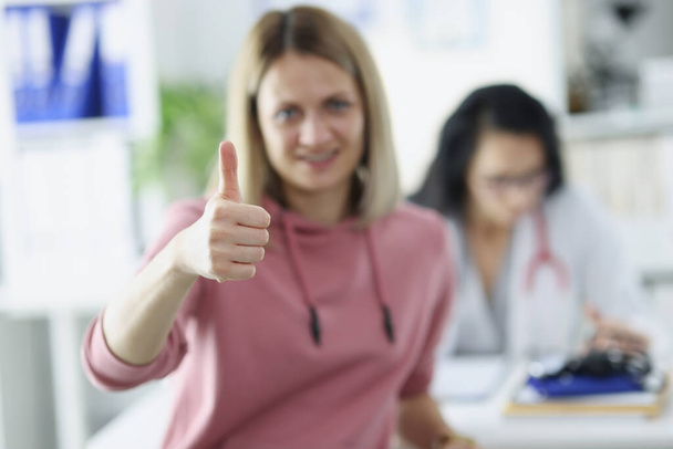 Молода жінка пацієнт тримає великий палець на призначенні лікаря
 - Фото, зображення