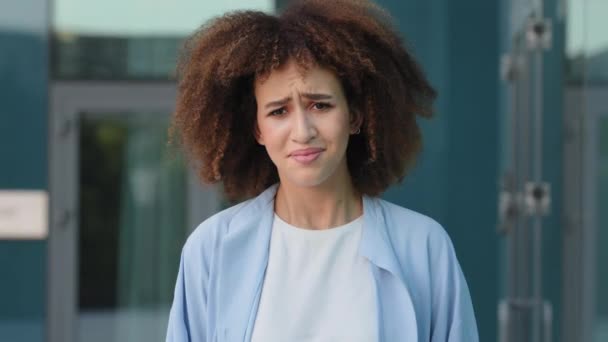 Kobieta portret na zewnątrz smutny stres afrykański amerykański dziewczyna młody zdenerwowany zdesperowany kobieta z kręconymi włosami pokrywa uszy z rąk z głośnym hałasem dźwięk trzymając głowę z ataku paniki ból horror problem - Materiał filmowy, wideo