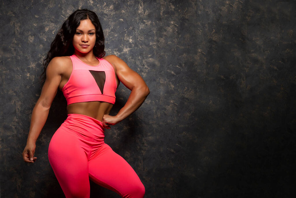 schöne starke junge Bodybuilderin Athletin posiert in fuchsia Sportbekleidung - Foto, Bild