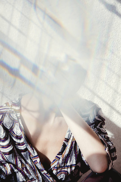 портрет молодої жінки в красивому одязі зі скляними спотвореннями і тінями на її обличчі. Сіра стіна на фоні
 - Фото, зображення
