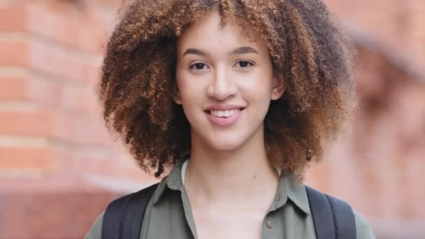 Closeup portrait of beautiful confident millennial african american woman with perfect fresh healthy face skin black curly hair. Attractive young mixed race female looking at camera posing outdoors - Záběry, video