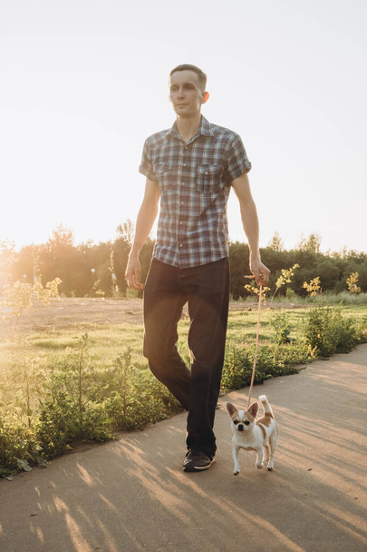 The blur effect. A young man walks in the park with a Chihuahua. - Фото, зображення