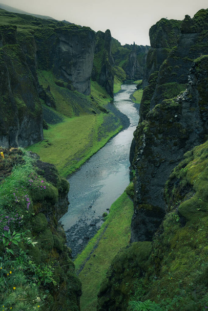 Epic aerial view of Fjadrargljufur Canyon in southern Iceland. A green lush canyon with steep rocks carved into picturesque landscape in moody hazy atmosphere. - Foto, imagen