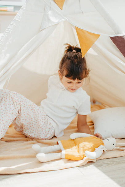 cute girl playing in teepee with fabric tilda bunny at home - Valokuva, kuva