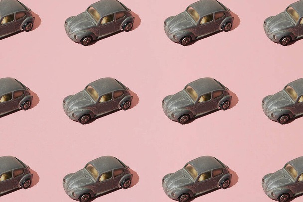 古い小さなおもちゃの金属ドイツ車のカブトムシを手配した。皮をむいた銀塗料。ピンクの背景。極小パターン. - 写真・画像