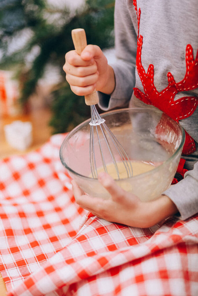 girl whips an egg white with a whisk to make cookies on the background of a christmas tre - Foto, immagini