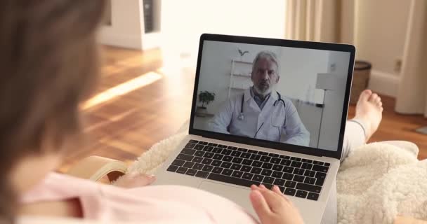 Young pregnant woman holding video call with older male obstetrician. - Video
