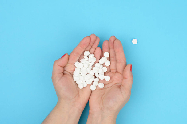 naisten käsi tilalla pyöreä valkoinen pillereitä sinisellä taustalla, kivunhoito, riippuvuus lääkkeistä, ylhäältä - Valokuva, kuva