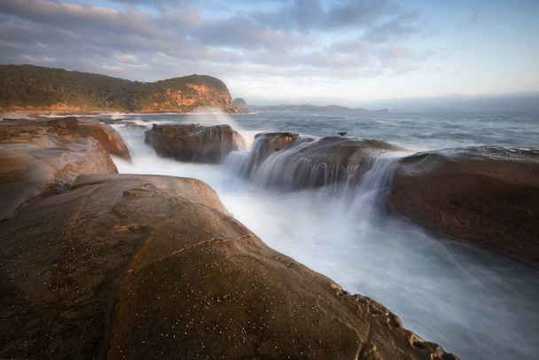 Водопад на скалах на пляже в утреннем сиянии - Фото, изображение