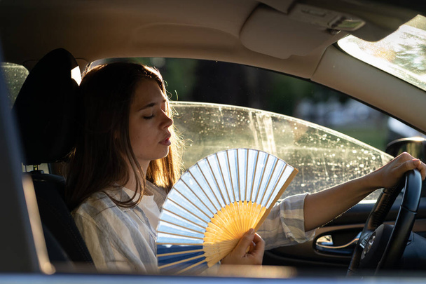 Chica conductor con ventilador de mano que sufre de calor en el coche, tiene problemas con el acondicionador de aire que no funciona - Foto, Imagen