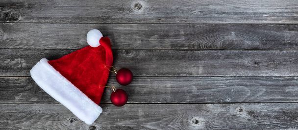Red Santa klobouk a míčové ozdoby na vybledlé dřevo pro veselé Vánoce nebo šťastný Nový rok svátky  - Fotografie, Obrázek