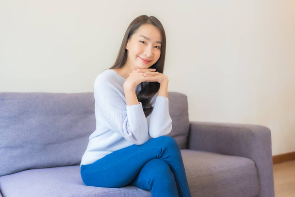 Retrato bonito jovem asiático mulher relaxar sorriso no sofá na sala de estar - Foto, Imagem
